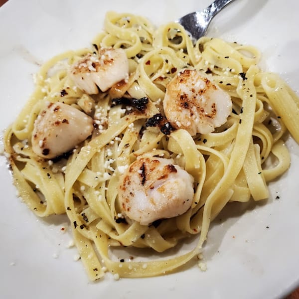 Ezio's Italian Restaurant's fettuccine pasta with seared scallops, grated cheese, and black pepper.
