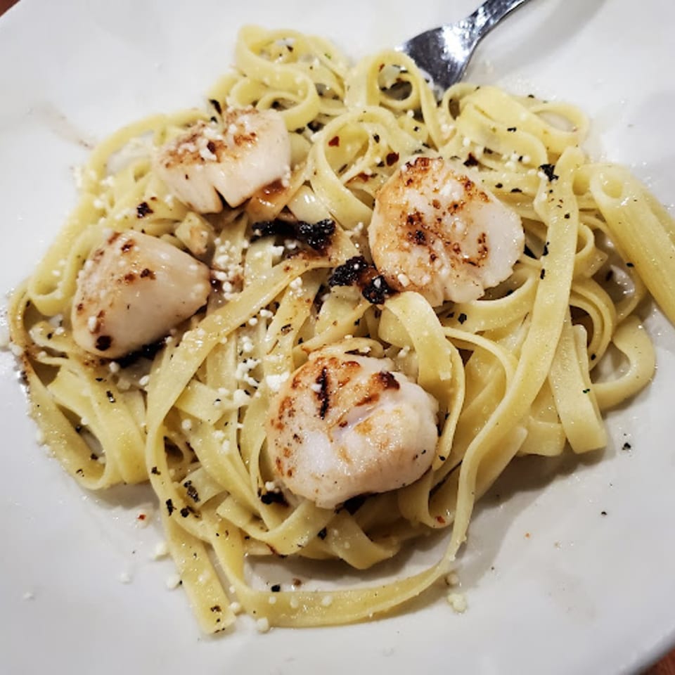 Ezio's Italian Restaurant's fettuccine pasta with seared scallops, grated cheese, and black pepper.