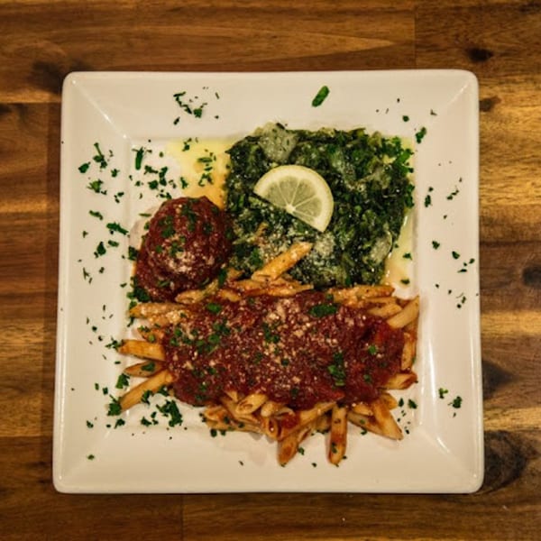 Ezio's Italian pasta with red sauce, a meatball, and spinach with a lemon slice.